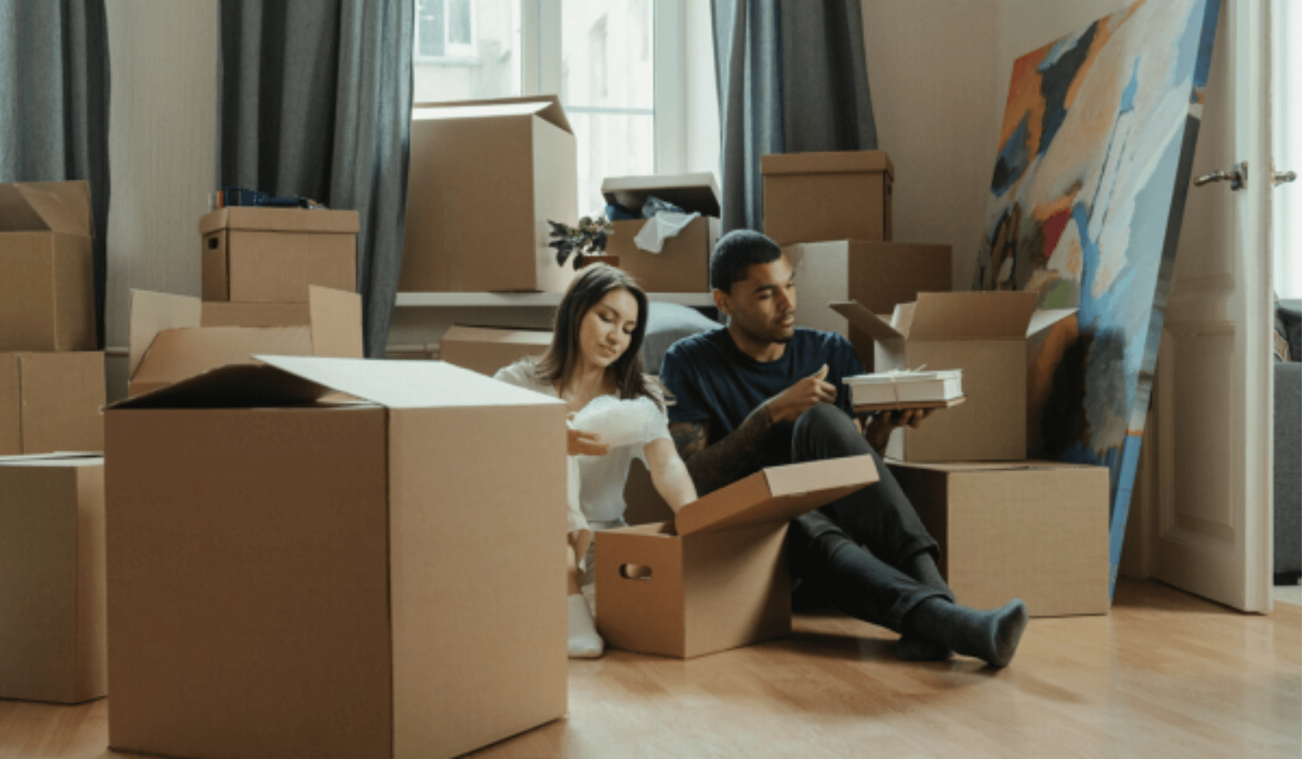 Un couple assis par terre au milieu de plein de cartons pour préparer leur déménagement