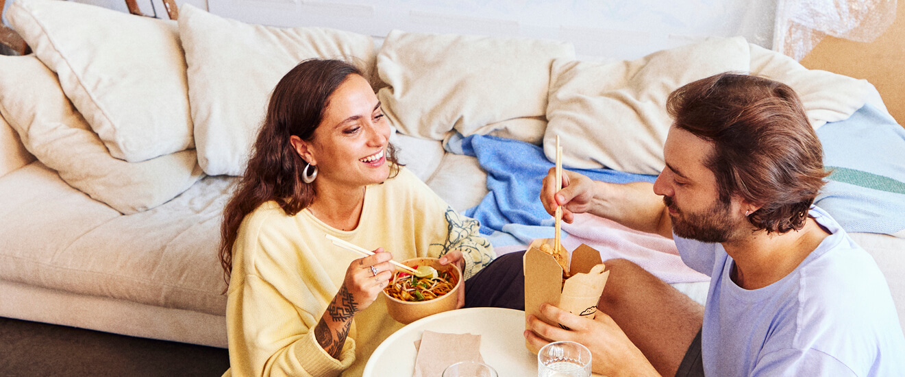 Una coppia mangia insieme cibo da asporto nel loro nuovo appartamento