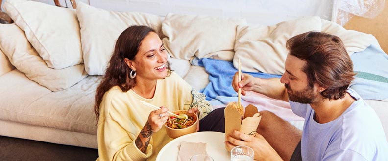 Couple qui mange un repas à l'emporter ensemble dans leur nouvel appartement
