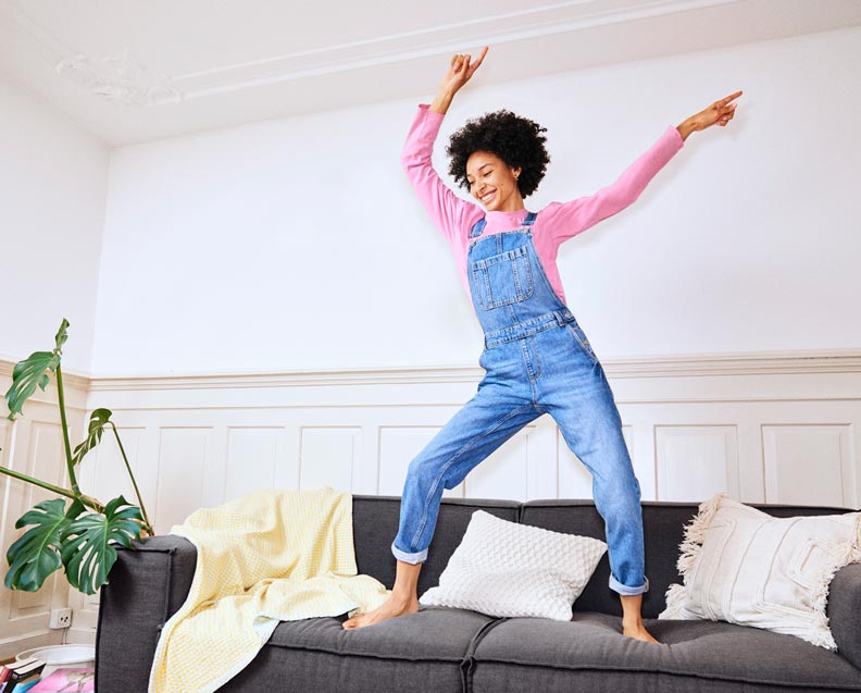 Jeunes femmes qui danse sur le canapé de son nouvel appartement