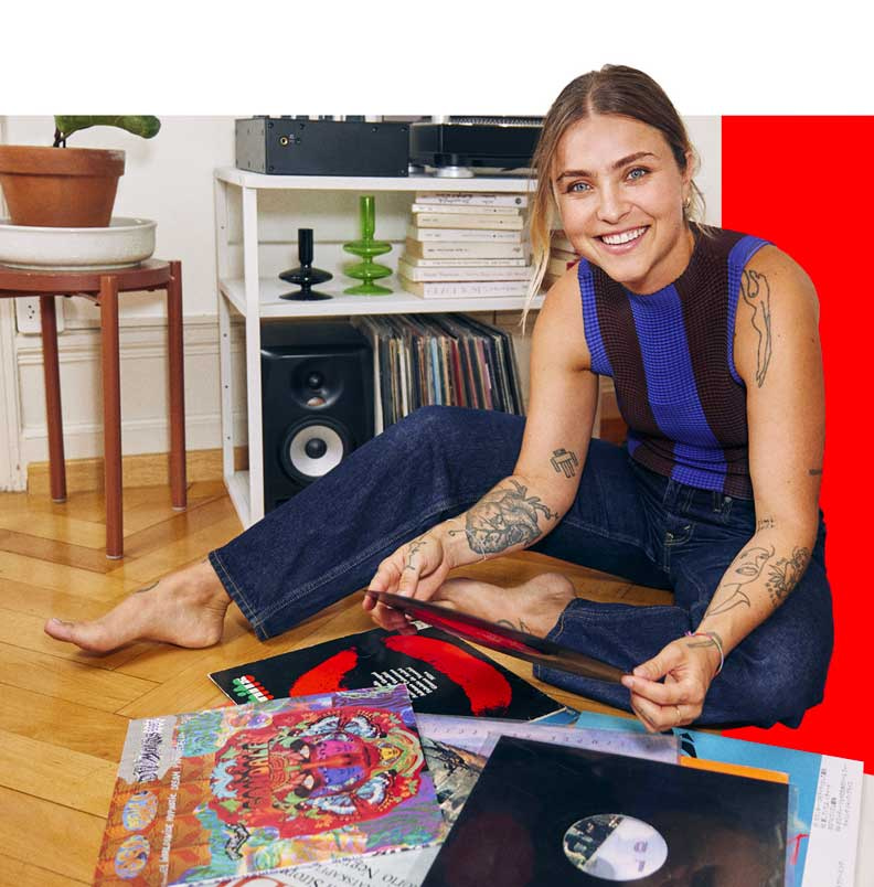 Une jeune femme assise dans sons salon avec ses vinyles