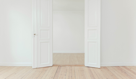 Bright flat with light wood flooring and open white doors