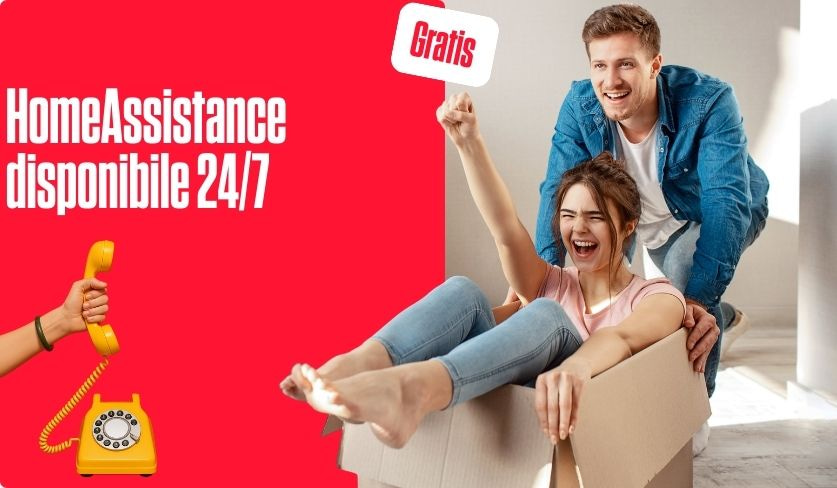 Una donna felice è seduta in uno scatolone da trasloco ed è spinta dal suo compagno.